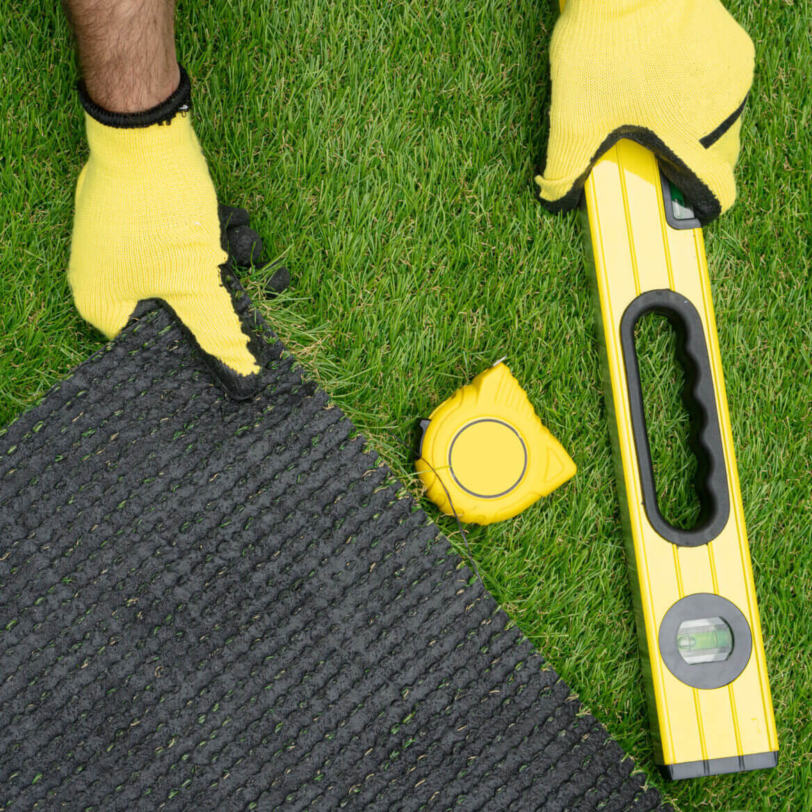 Man's Hands With The Artificial Grass Roll And Tools