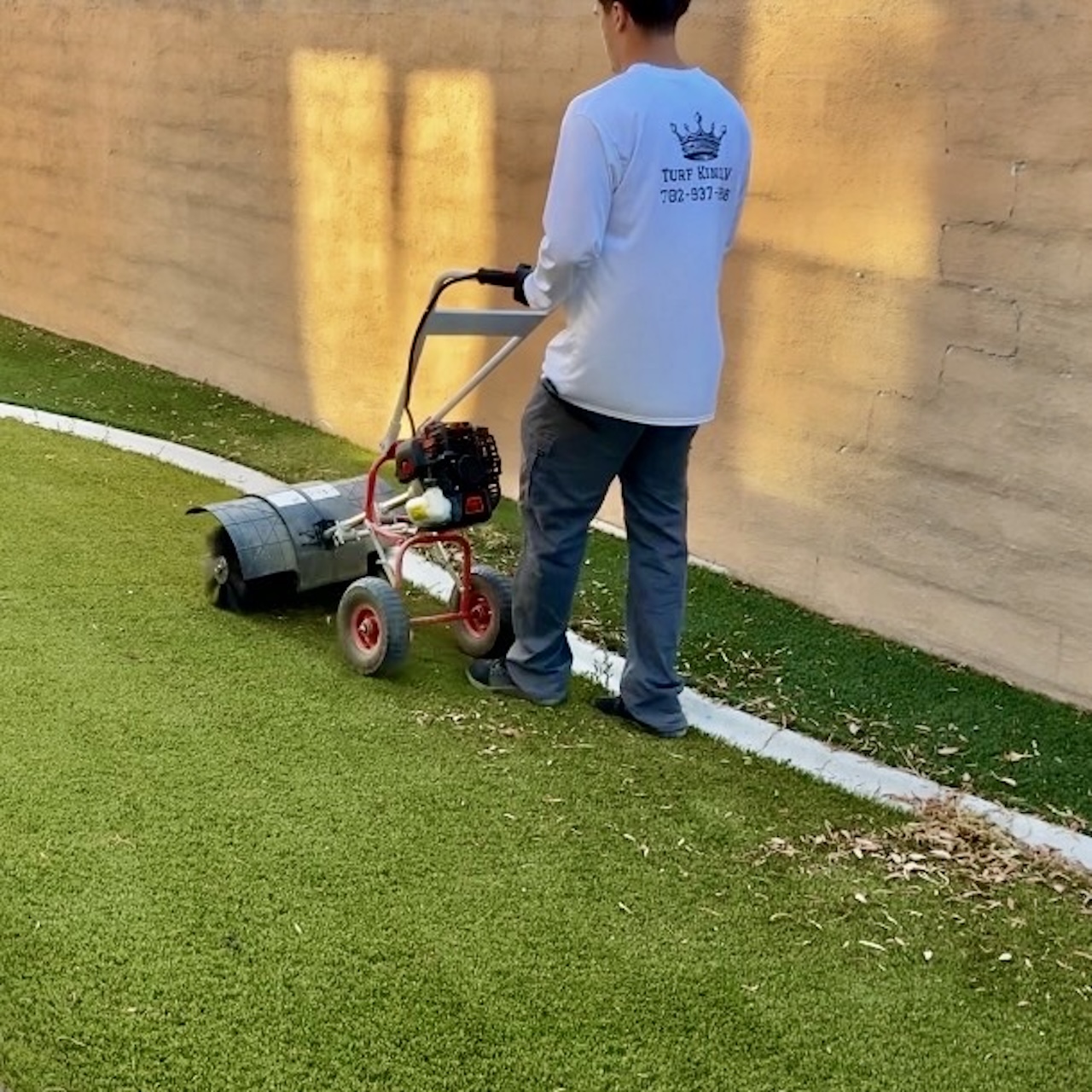 Turf King LV technician professionally power brushing artificial turf at a Las Vegas residential property